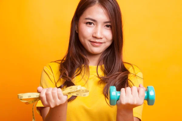 Gezonde Aziatische vrouw met halters en meetlint in geel — Stockfoto