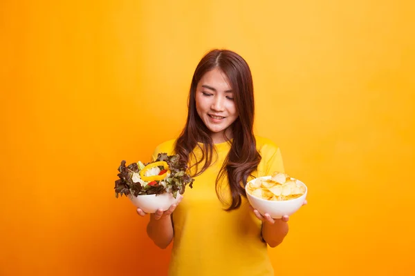 Jovem mulher asiática com batatas fritas e salada em vestido amarelo — Fotografia de Stock