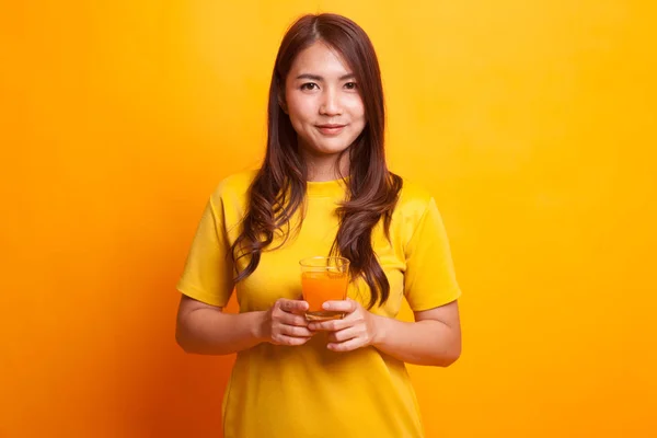 Молодая азиатка пьет апельсиновый сок в желтом платье — стоковое фото