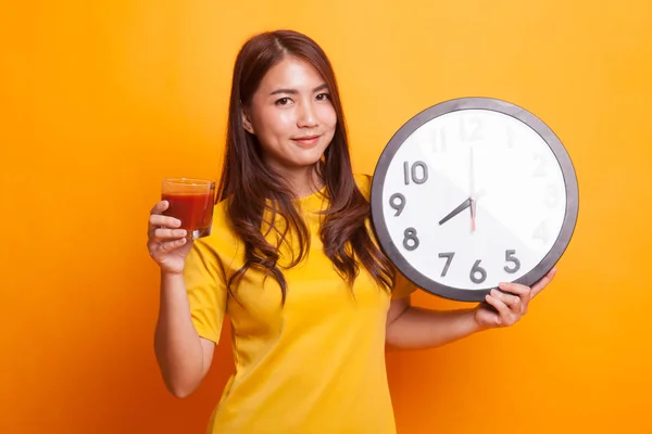 年轻的亚洲妇女与蕃茄汁和时钟在黄色礼服 — 图库照片