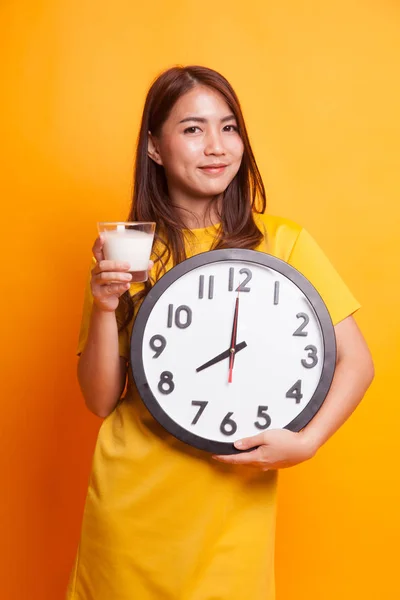 Mulher asiática saudável beber copo de leite segurar relógio em amarelo — Fotografia de Stock