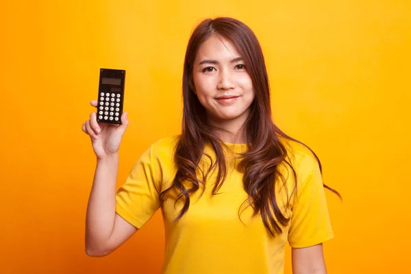 Asiatin lächelt mit Taschenrechner im gelben Kleid — Stockfoto