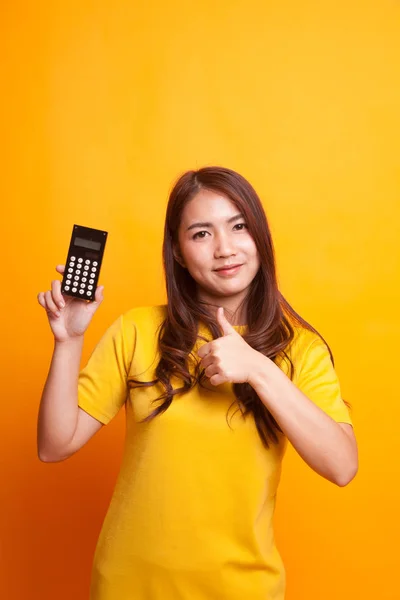 Asiatische Frau Daumen hoch mit Taschenrechner in gelbem Kleid — Stockfoto