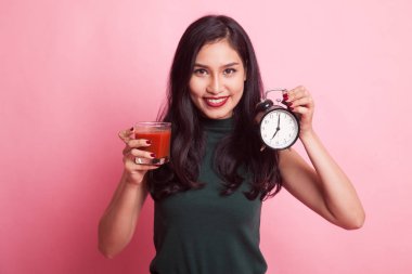 Domates suyu ve saat ile genç Asyalı kadın.