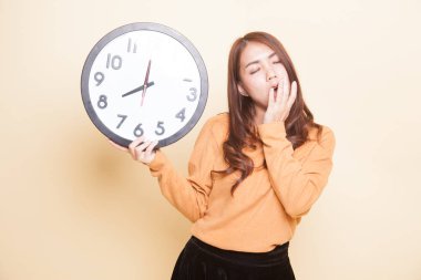 Sabah bir saat ile uykulu genç Asyalı kadın.