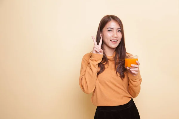Mladá asijská žena nenasvědčuje vítězství pít pomerančový džus. — Stock fotografie