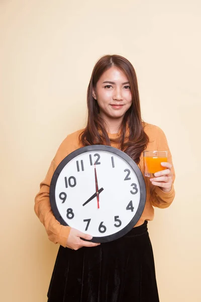 Aziatische vrouw met een klok drankje oranje sap. — Stockfoto