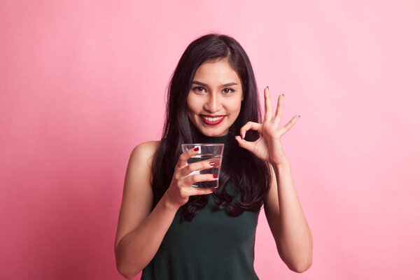 Young Asian woman show OK with a glass of drinking water.
