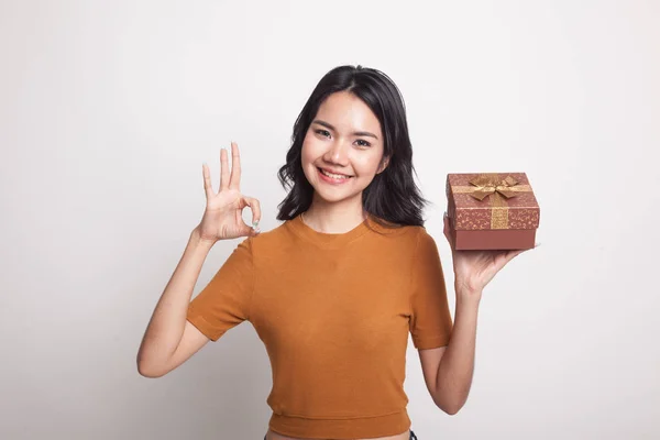 Молодая азиатка показывает ОК с подарочной коробкой . — стоковое фото