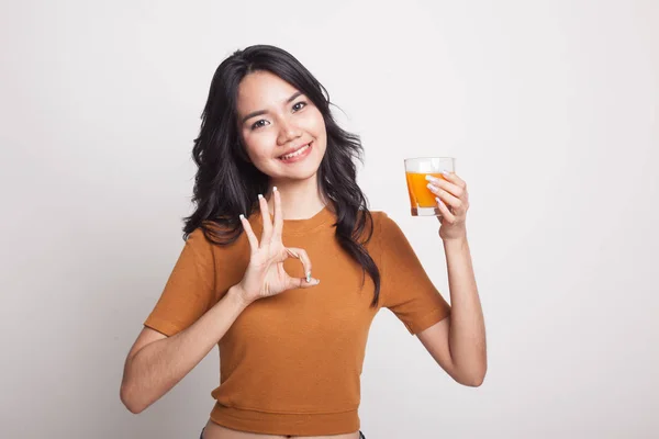 Jovem mulher asiática mostrar OK beber suco de laranja . — Fotografia de Stock