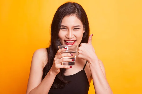 Jovem mulher asiática polegares para cima com um copo de água potável . — Fotografia de Stock
