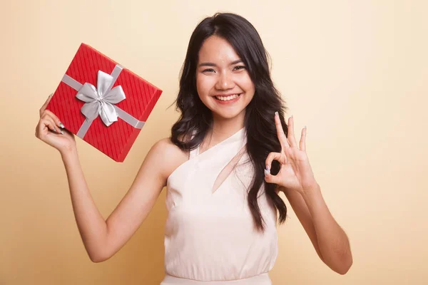 Junge asiatische Frau zeigen ok mit ein Geschenk-Box. — Stockfoto