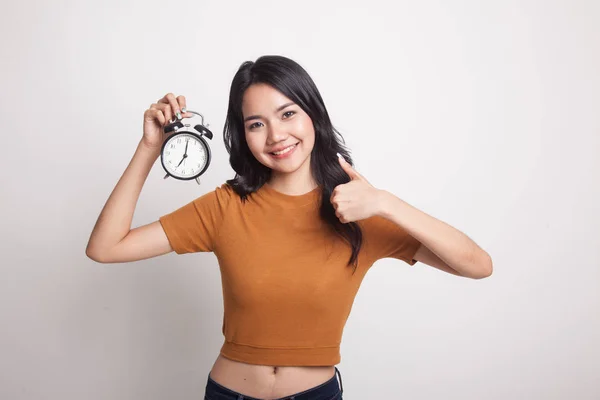 Jeune asiatique femme montrer pouces vers le haut avec une horloge . — Photo