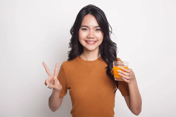 Jovem mulher asiática mostrar vitória sinal bebida suco de laranja . — Fotografia de Stock