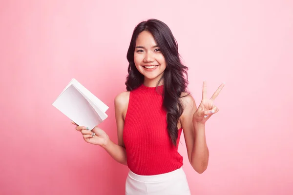 Young Asian woman show victor sign with a book. — Stock Photo, Image
