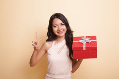 Genç Asyalı kadın göstermek zafer işareti ile bir hediye kutusu.
