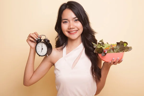 Young Asian woman with clock and salad. — Stock Photo, Image