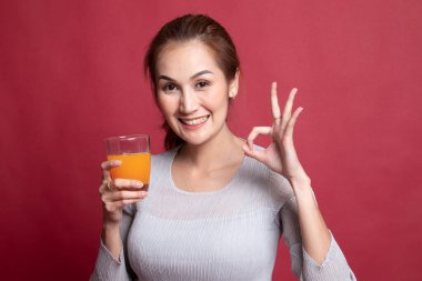 Genç Asyalı kadın içki portakal suyu göster Ok işareti.