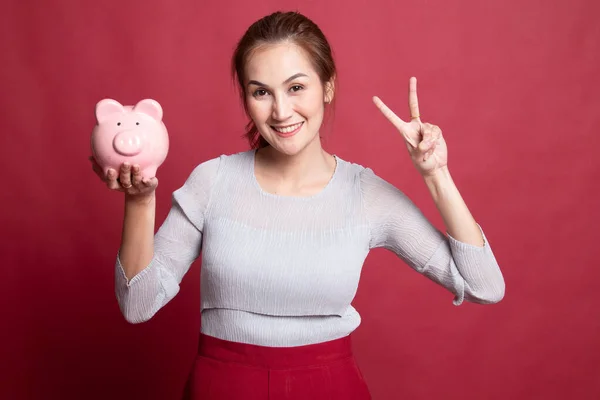 Asiática mujer mostrar victoria signo con cerdo moneda banco . —  Fotos de Stock