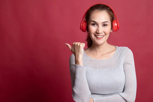 Bastante asiático chica escuchar música con su auriculares punto a c — Foto de Stock