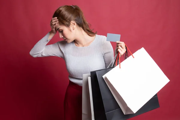 Mujer asiática joven infeliz con bolsas de compras y tarjeta de crédito . — Foto de Stock