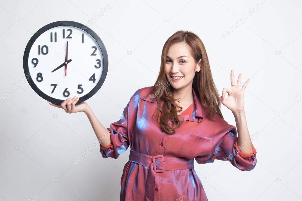 Young Asian woman show OK with a clock.