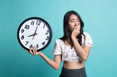 Sabah bir saat ile uykulu genç Asyalı kadın.