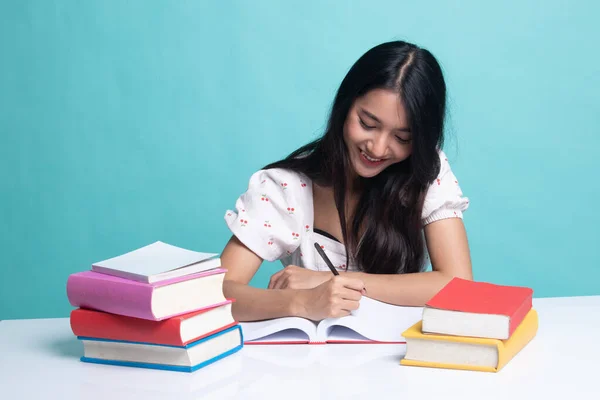 Ung asiatisk kvinna läsa en bok med böcker på bord. — Stockfoto