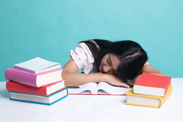 Uitgeput jonge Aziatische vrouw slapen met boeken op tafel. — Stockfoto