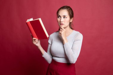 Bir kitapla genç Asyalı kadın düşünüyor.