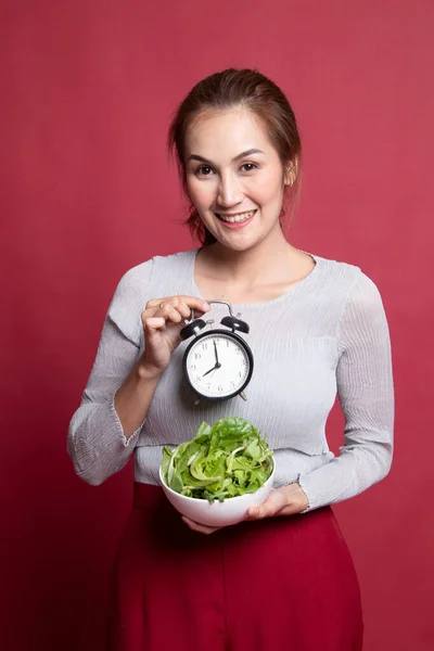 Jonge Aziatische vrouw met klok en salade. — Stockfoto