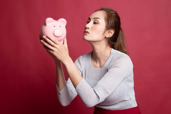 Junge asiatische Frau küssen eine rosa Münzbank. — Stockfoto