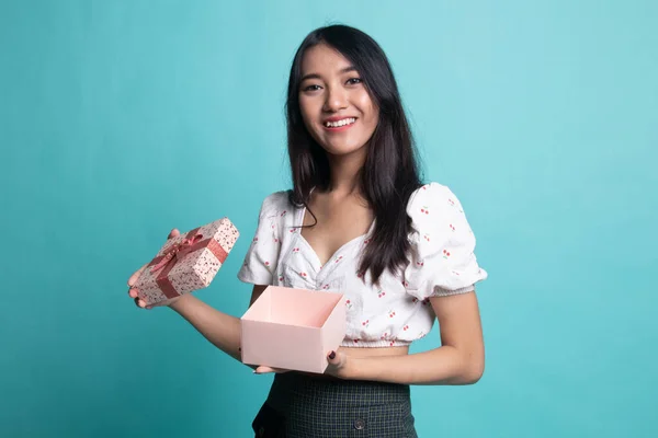 年轻的亚洲女人打开一个蓝色背景的金色礼品盒 — 图库照片