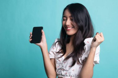  Cyan arka planında cep telefonu olan mutlu Asyalı kadın.