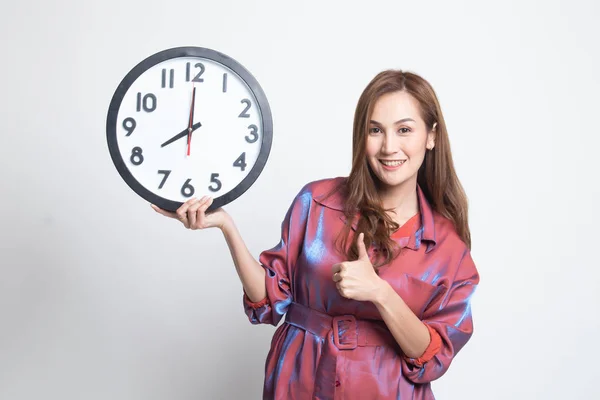 Young Asian woman thumbs up with a clock. — Stock Photo, Image