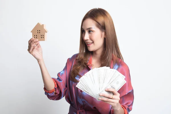 Feliz joven asiática mujer con casa modelo y montón de dinero banco —  Fotos de Stock