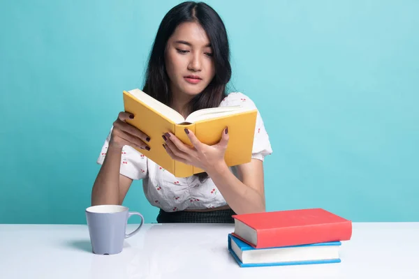 Mladá asijská žena číst knihu s šálkem kávy. — Stock fotografie
