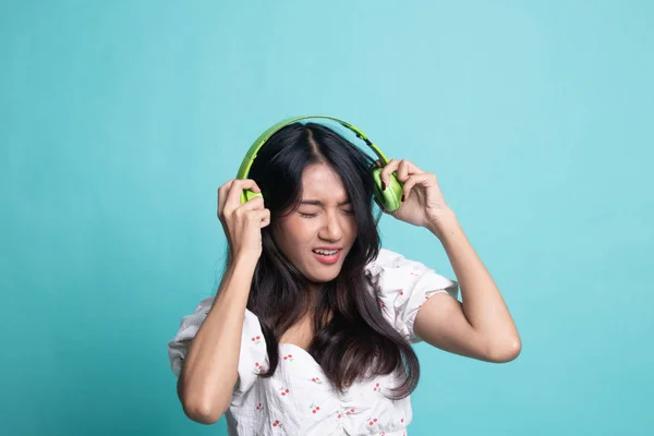 Too loud.  portrait of  young asian woman  holding  headphones a