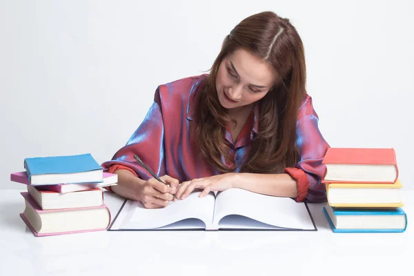 Joven mujer asiática leer un libro con libros en la mesa . — Foto de Stock