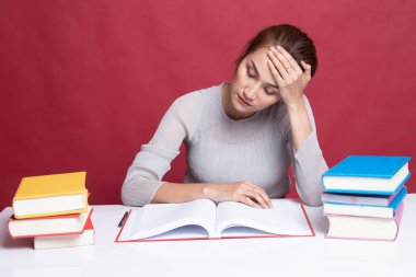 Yorgun genç Asyalı kadın kitapları tablo ile bir kitap okumak.