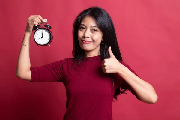 Jeune asiatique femme montrer pouces vers le haut avec une horloge . — Photo