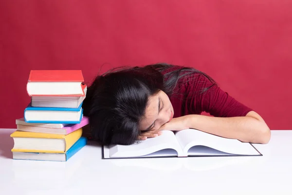 Uitgeput jonge Aziatische vrouw slapen met boeken op tafel. — Stockfoto