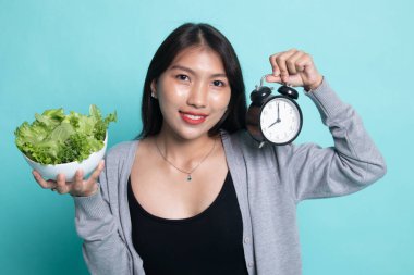 Saat ve salata ile genç Asyalı kadın.