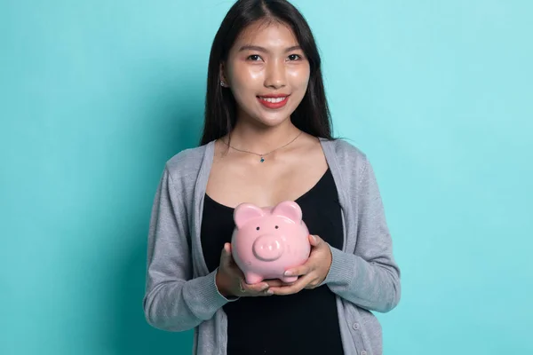 Jovem mulher asiática com um banco de moedas de porco . — Fotografia de Stock