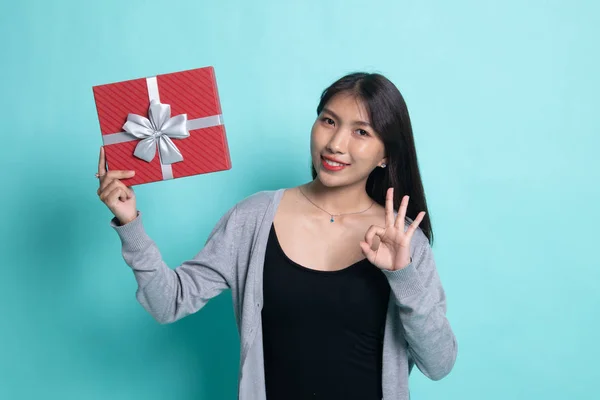 Молодая азиатка показывает ОК с подарочной коробкой . — стоковое фото