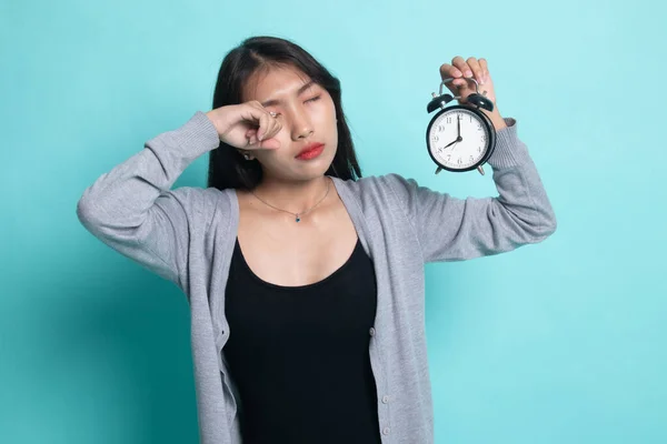 Sömnig ung asiatisk kvinna med en klocka på morgonen. — Stockfoto