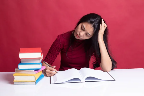 Mujer asiática joven agotada leer un libro con libros en la mesa . — Foto de Stock
