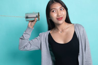 Teneke kutu telefon ile genç Asyalı kadın.