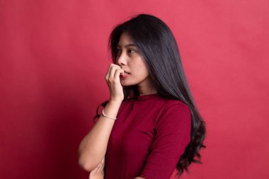 Tereddütlü, sinirli, genç Asyalı kadın tırnağını yiyor.