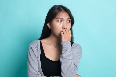 Tereddütlü, sinirli, genç Asyalı kadın tırnağını yiyor.